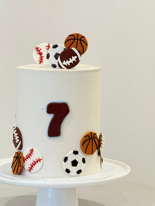 White cake with sports-themed decorations on a white background