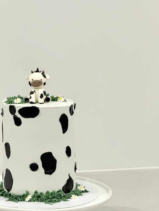 Millie kids birthday cake top view — cow print pattern with grass border and daisies — Bakeology Studios Melbourne