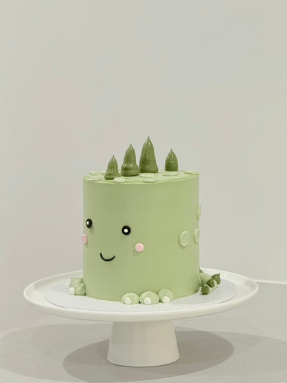 Dino style sage green smiley face kids birthday cake with pine tree toppers — Bakeology Studios Melbourne
