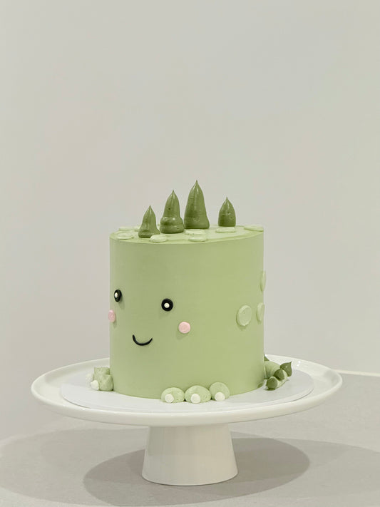 Dino style sage green smiley face kids birthday cake with pine tree toppers — Bakeology Studios Melbourne
