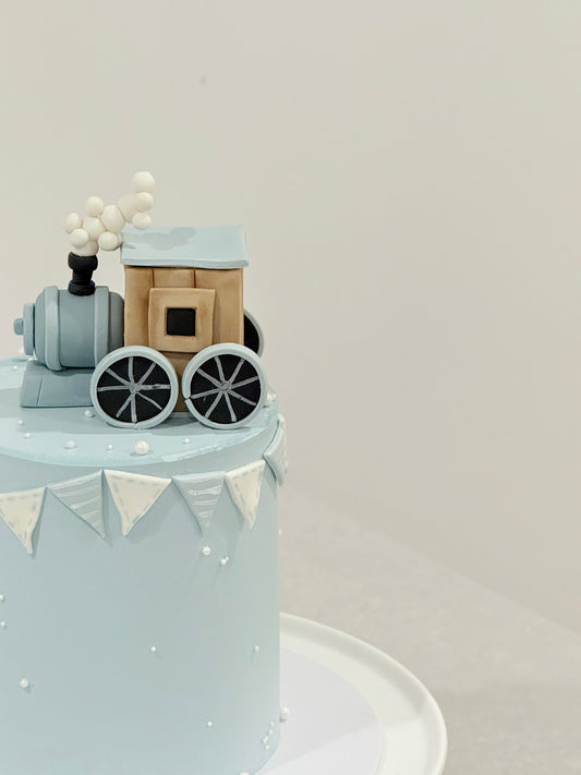 Small train model on a cake with a plain background