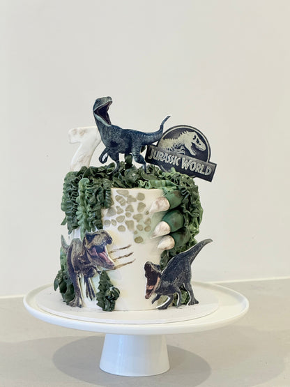 Blue Jurassic World dinosaur themed kids birthday cake with figurines — Bakeology Studios Melbourne