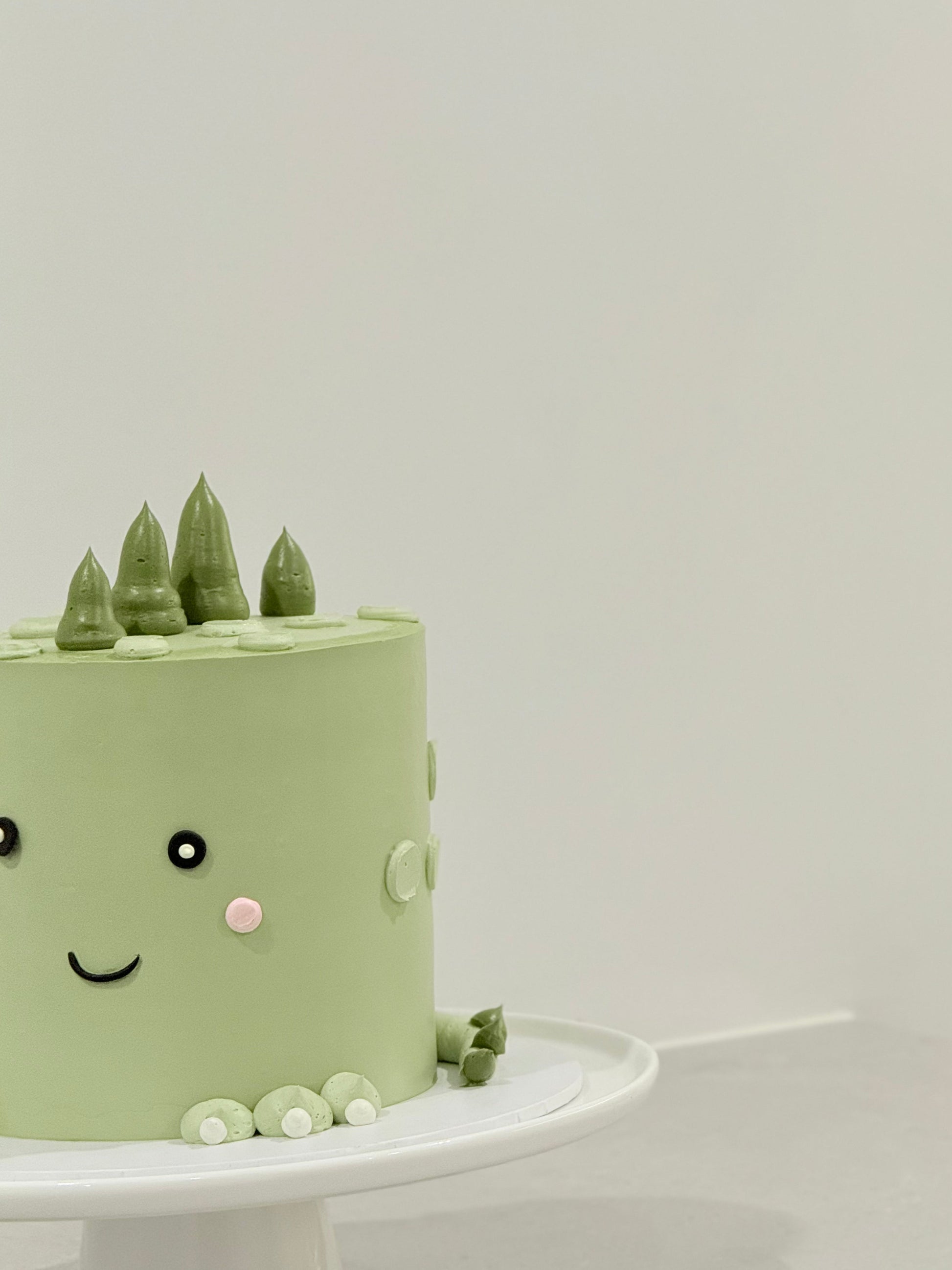Sage green dino kids birthday cake with buttercream pine trees — custom handcrafted Melbourne