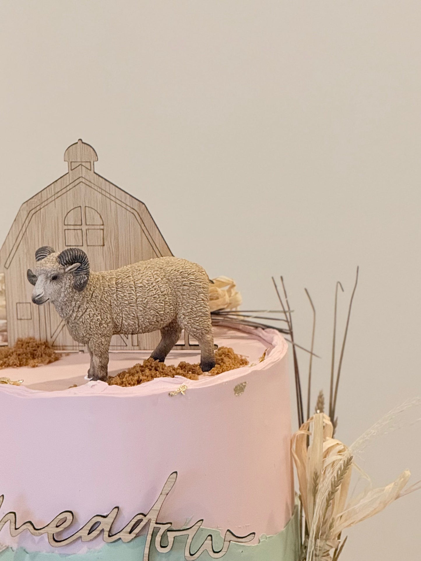 Decorative display with a ram figure on a pink platform against a neutral background