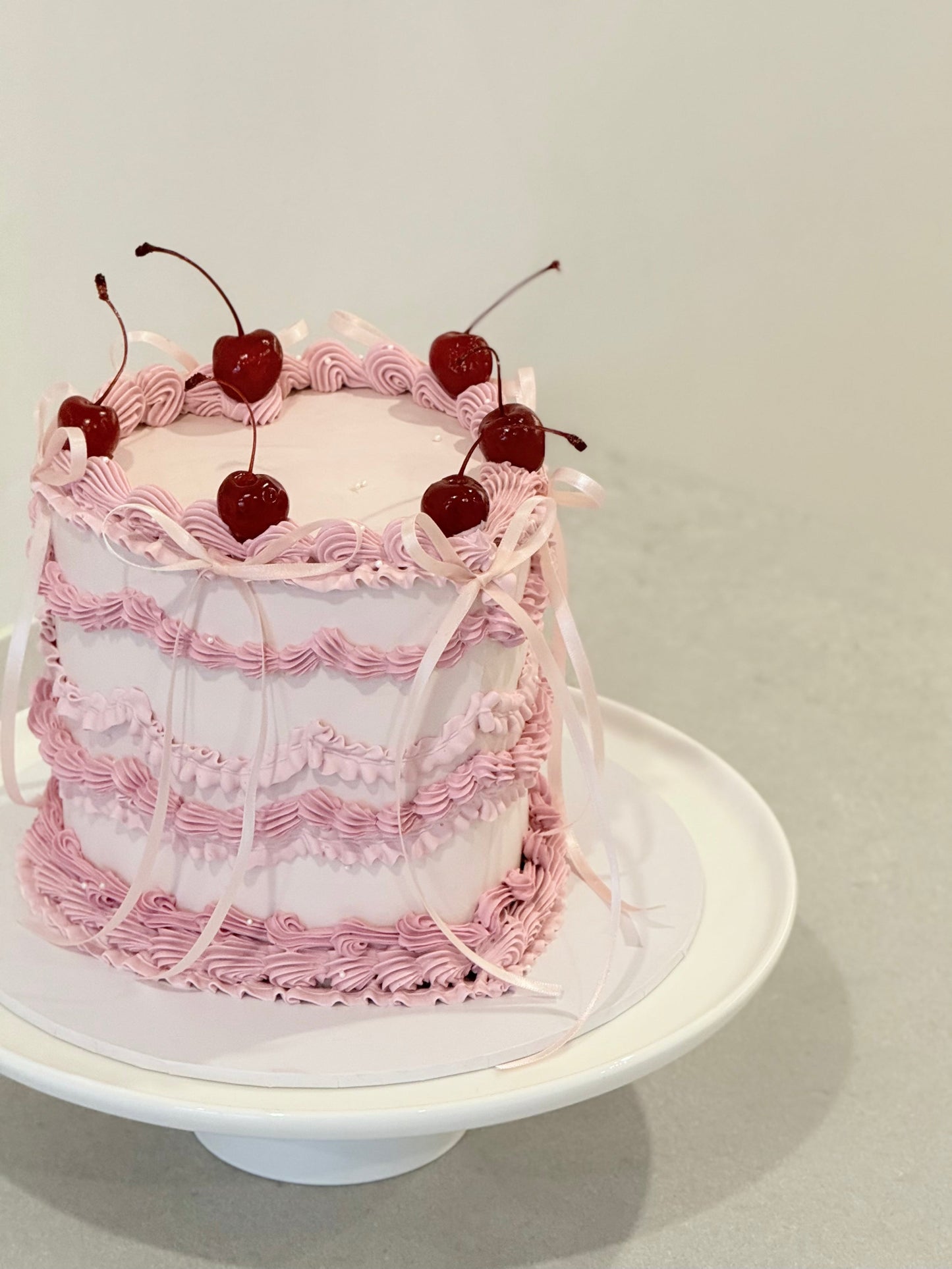 Lola vintage ruffle cake top view — fresh cherries and pink ribbon detail — Bakeology Studios Melbourne