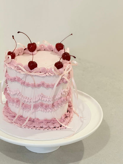 Lola vintage ruffle cake top view — fresh cherries and pink ribbon detail — Bakeology Studios Melbourne