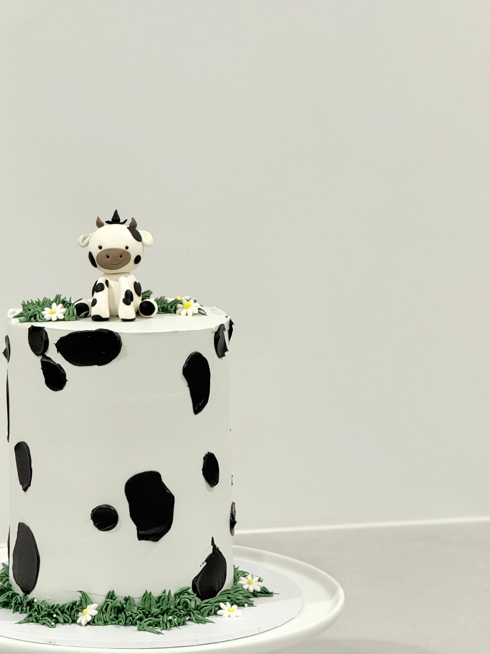 Millie kids birthday cake top view — cow print pattern with grass border and daisies — Bakeology Studios Melbourne