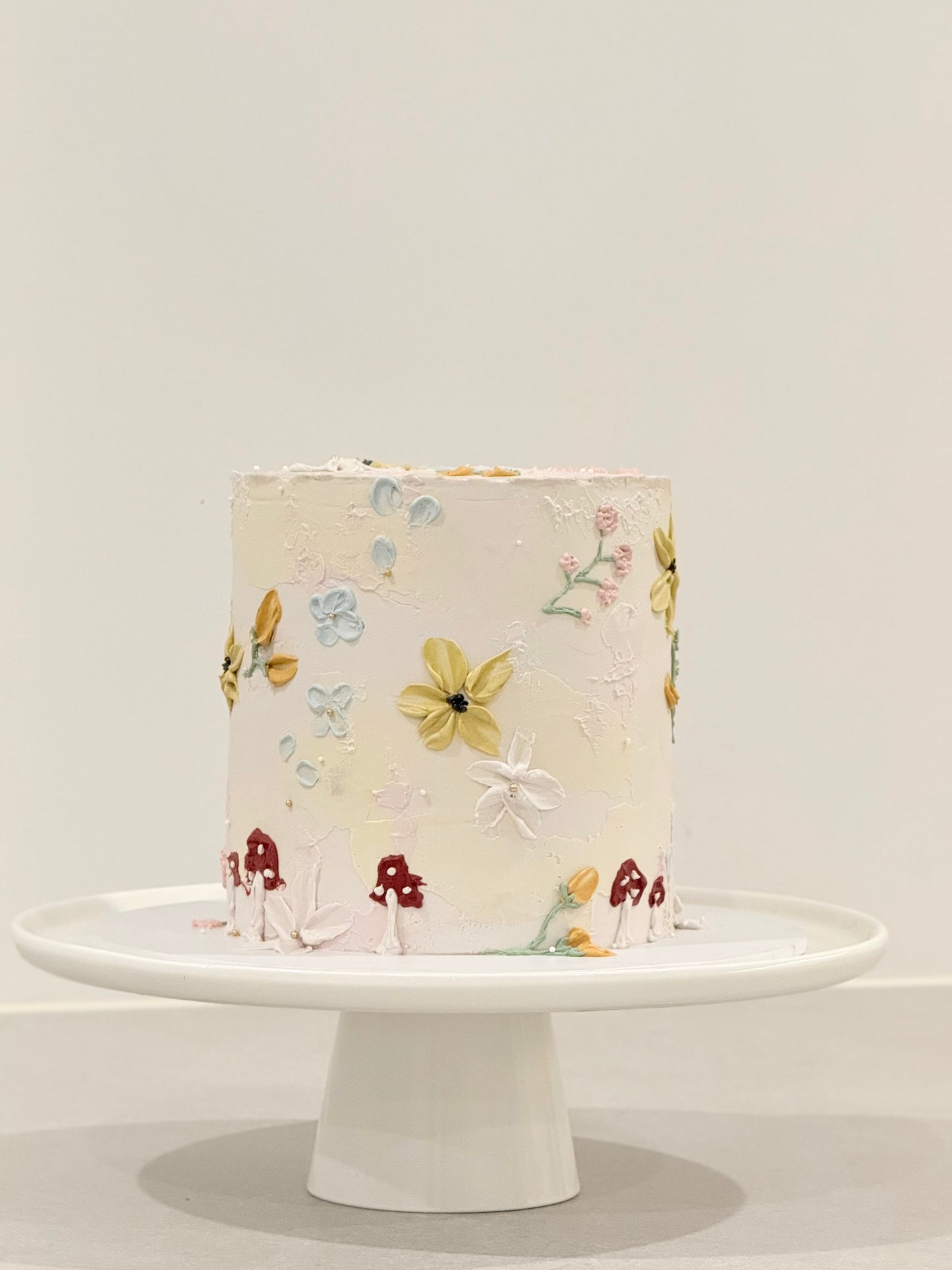 Decorative cake with floral patterns on a white stand against a light gray background