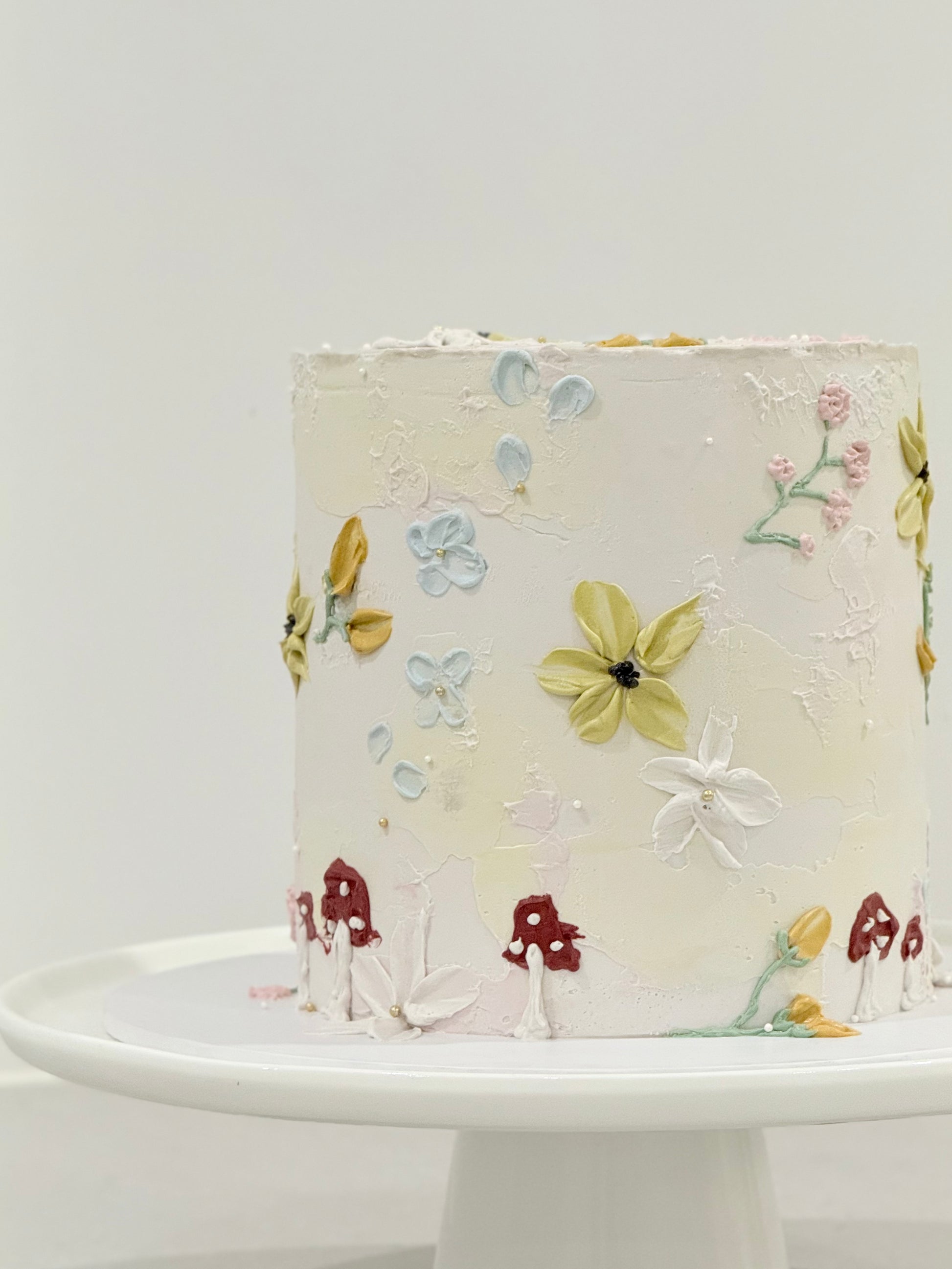 Decorative cake with floral designs on a white stand against a light gray background