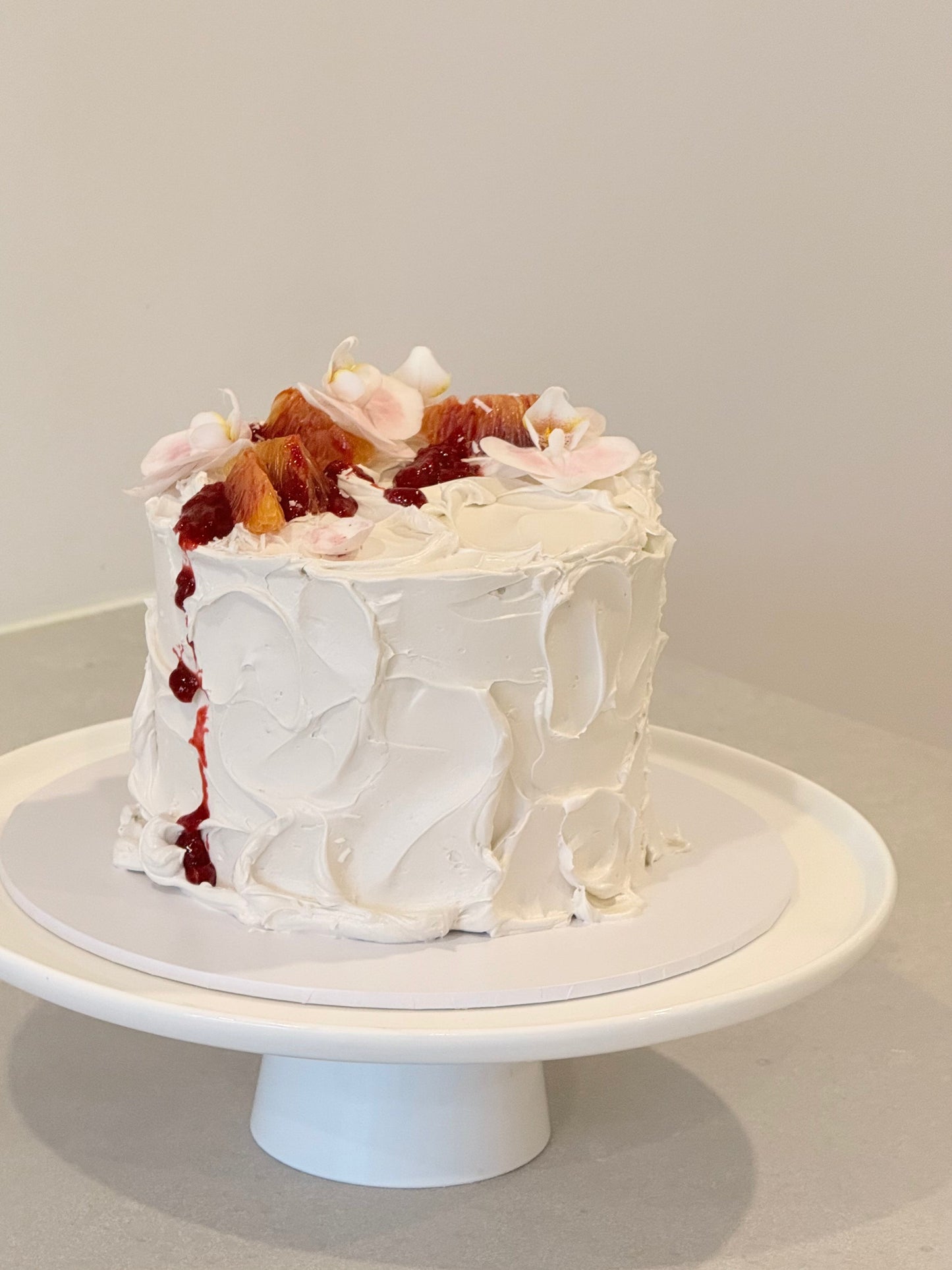 Top view of rustic white buttercream cake with dried fruit and floral topping — Bakeology Studios Melbourne