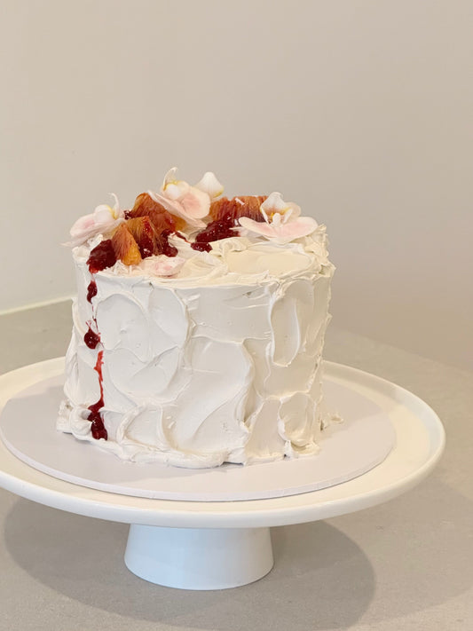 Top view of rustic white buttercream cake with dried fruit and floral topping — Bakeology Studios Melbourne